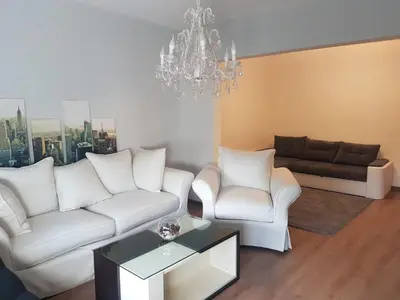 a living room with white furniture and a chandelier at Odessus in Varna City