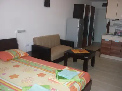 a room with two beds and a chair and a kitchen at Ganozliev's Apartments in Kavatsi Area in Sozopol