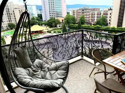 a swinging chair on a balcony with a view of a city at Royal Beach Premium in Sunny Beach