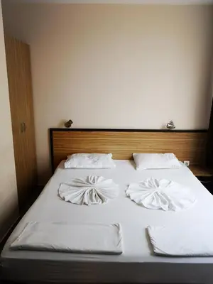 a bed with white sheets and pillows on it at Hotel Varly Bryag in Burgas City