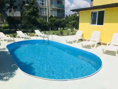 a swimming pool with white chairs and a blue swimming pool at Hotel Elmaz in Lozenets