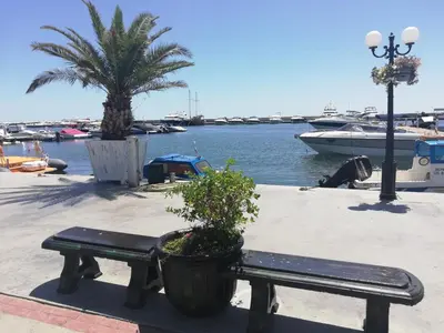 a bench sitting next to a marina with a boat at Galateya Sveti Vlas Bułgaria in Sveti Vlas