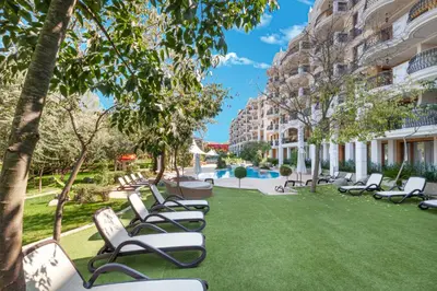 a row of lounge chairs on a lawn in front of a building at Harmony Suites Grand Resort in Sunny Beach