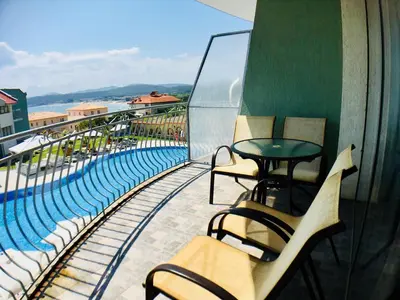 a balcony with chairs and a table and a pool at Gardenia Suites in Sozopol