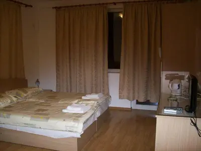 a bedroom with a bed and a television and curtains at Guest House Donchevi in Primorsko
