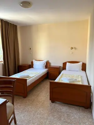 a room with two beds and a table and chairs at Family Hotel Chris in Sveti Vlas