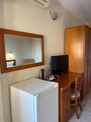 a kitchen with a refrigerator and a desk with a mirror at Family Hotel Chris in Sveti Vlas