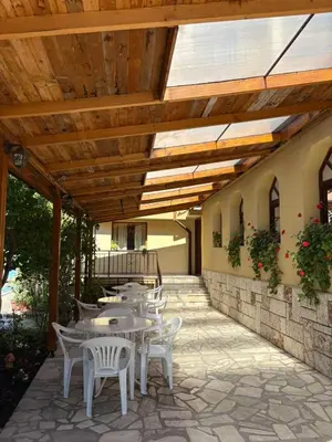 a patio with tables and chairs under a wooden roof at Family Hotel Chris in Sveti Vlas