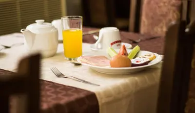a plate of fruit on a table with a glass of orange juice at Family Hotel Saint Iliya in Burgas City