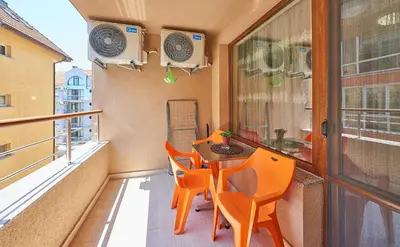 a balcony with orange chairs and a table and a window at Апартаменти 
