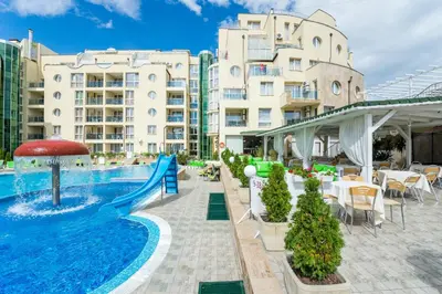 a pool at a hotel with tables and chairs and a slide at Apart Hotel Vechna R in Sunny Beach