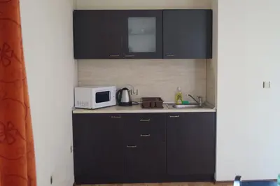 a kitchen with black cabinets and a white microwave at Апартхотел Созополски перли in Sozopol