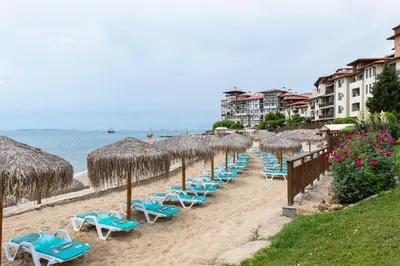 a row of chairs and umbrellas on a beach at Garden of Eden Complex in Sveti Vlas
