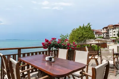 a wooden table and chairs on a balcony overlooking the ocean at Garden of Eden Complex in Sveti Vlas