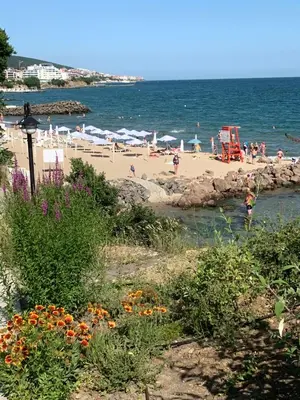 a beach with people on the sand and the ocean at Private Apartment 49 in Prestige Fort Beach Hotel in Sveti Vlas