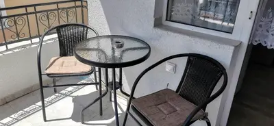 a glass table and two chairs on a balcony at Къща за гости Слънчевият ъгъл - The sunny corner in Sozopol