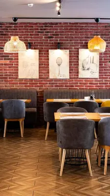 a restaurant with tables and chairs and a brick wall at Avenue Hotel Deluxe in Burgas City