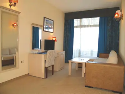 a living room with a couch and a desk with a television at Grenada Hotel in Sunny Beach