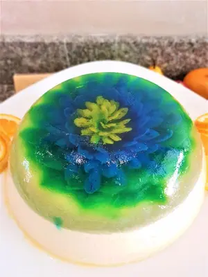 a green and blue cake with a flower on a plate at Grenada Hotel in Sunny Beach