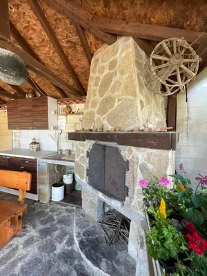 a stone fireplace in a kitchen with flowers at The White House in Bliznatsi