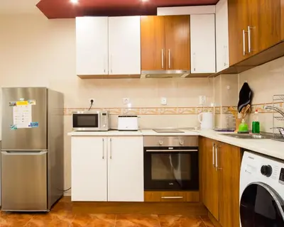 a kitchen with white cabinets and a stainless steel refrigerator at Aleksapart in Burgas City