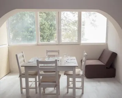 a white table and chairs in a room with windows at Aleksapart in Burgas City