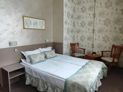 a bedroom with a large bed and two chairs at Семеен Хотел 