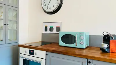 a microwave sitting on a counter with a clock on the wall at APARTELLO Modern Apartment - Balkan Breeze 7 in Sunny Beach
