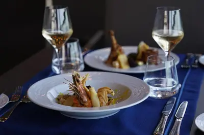 a table with two plates of food and glasses of wine at HVD Clubhotel Miramar - 24 Hours Ultra All Inclusive & Free Parking in Obzor