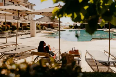 a woman sitting in a chair next to a pool at HVD Clubhotel Miramar - 24 Hours Ultra All Inclusive & Free Parking in Obzor