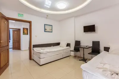 a room with two beds and a table and a tv at СТАИ ЗА ГОСТИ ХАН КРУМ in Burgas City