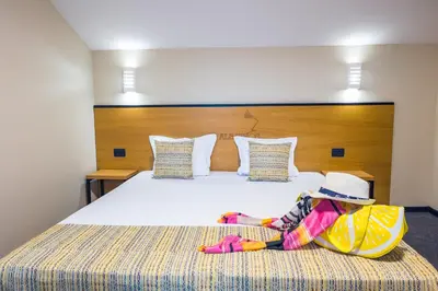 a child with a hat sitting on a bed at Hotel Albatros New Town in Sozopol