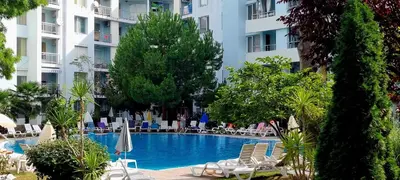 a swimming pool with chairs and umbrellas in a hotel at Niko Apartments in Sunny Beach