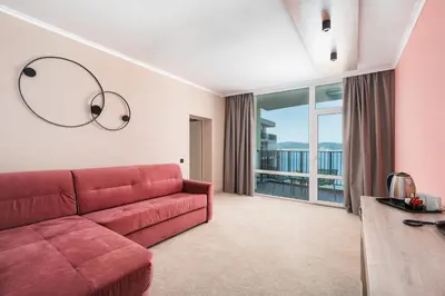 a living room with a red couch and a large window at Festa Panorama Hotel in Nesebar