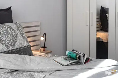 a bedroom with a bed with a book and a lamp at Photo Art apartment in Burgas City