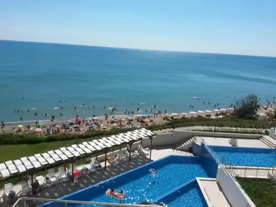 an aerial view of a beach with a swimming pool and umbrellas at By The Cliffs apartments in Byala