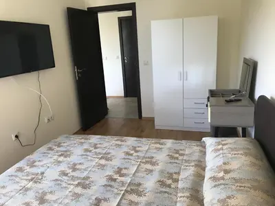 a bedroom with a bed and a desk and a tv at By The Cliffs apartments in Byala