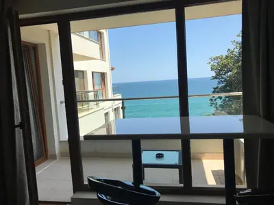 a view of the ocean from a balcony with a table and chairs at By The Cliffs apartments in Byala
