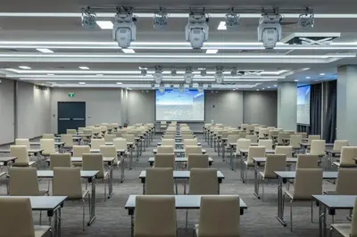 an empty room with tables and chairs and a projection screen at Hotel Bulgaria in Burgas City