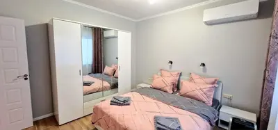 a bedroom with a bed with pink pillows and a mirror at GG Garden Deluxe in Chernomorets