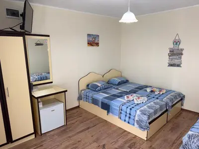 a bedroom with a bed with a blue comforter and a mirror at Villa SUN in Kiten