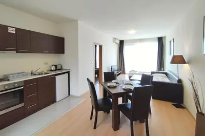 a kitchen and living room with a table and chairs at New Line Village Apartments in Sunny Beach
