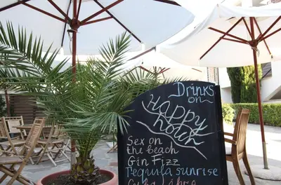 a sign that says drinks on my happy nightsaw on the beach in the backyard at New Line Village Apartments in Sunny Beach