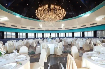 a banquet hall with white tables and chairs and a chandelier at Planeta Hotel & Aquapark FREE Beach Access - ULTRA All Inclusive in Sunny Beach