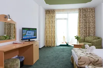 a hotel room with a bed and a desk with a television at Mena Palace Hotel - All Inclusive in Sunny Beach