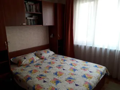 a bedroom with a bed with a comforter and a window at Family style, main street, 20 minutes from the sea in Burgas City