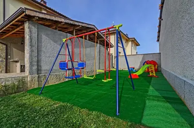 a playground with a slide and swings on the grass at Alex Village in Shkorpilovtsi