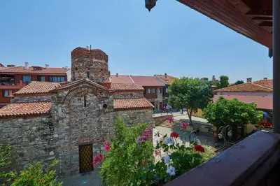 an old stone building with flowers in front of it at Hotel Saint John Baptist Nessebar in Nesebar