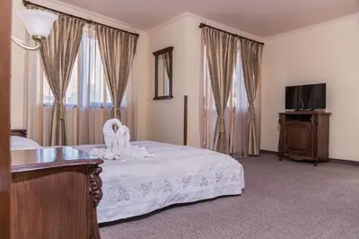 a bedroom with a bed and a tv and curtains at Hotel Saint John Baptist Nessebar in Nesebar
