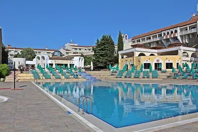 a large swimming pool with chairs and a building at Duni Pelican Hotel - All Inclusive in Sozopol
